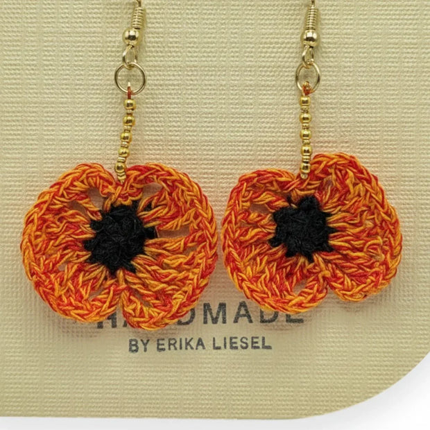 Handmade by Erika Liesel orange and black crochet poppy flower earrings with gold bead accents and gold hooks.