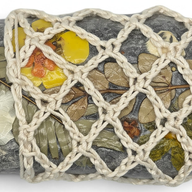 Handmade by Erika Liesel crochet stone sleeve featuring a natural grey stone adorned with pressed flowers and leaves.