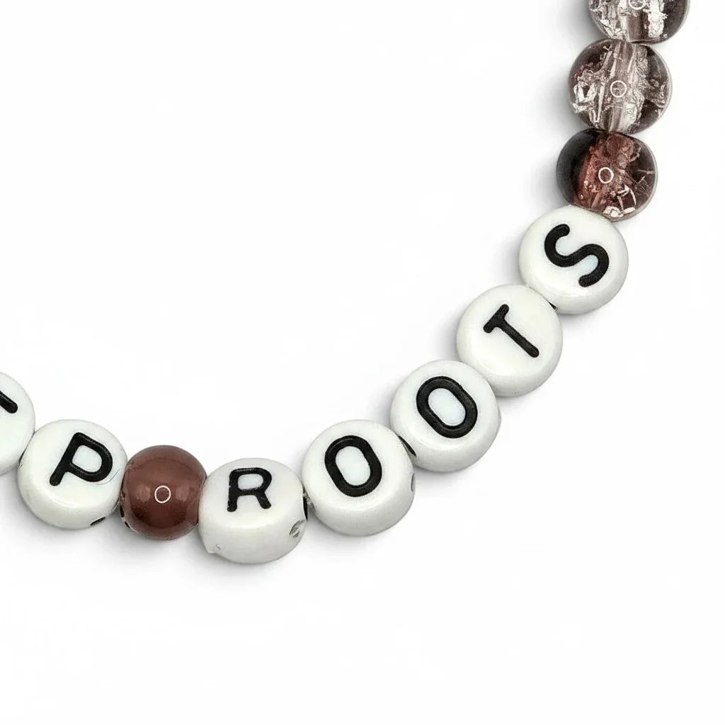 Handmade by Erika Liesel Deep Roots stretch bracelet with smoky brown crackle glass beads and white letter beads.