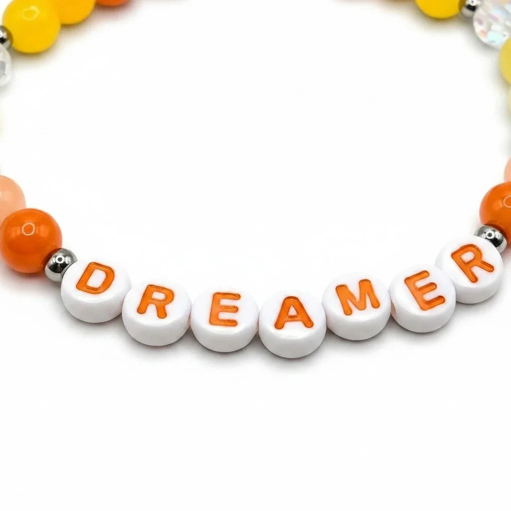 Handmade by Erika Liesel Dreamer stretch bracelet with white letter beads, orange accents, and sterling silver beads.