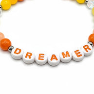 Handmade by Erika Liesel Dreamer stretch bracelet with white letter beads, orange accents, and sterling silver beads.