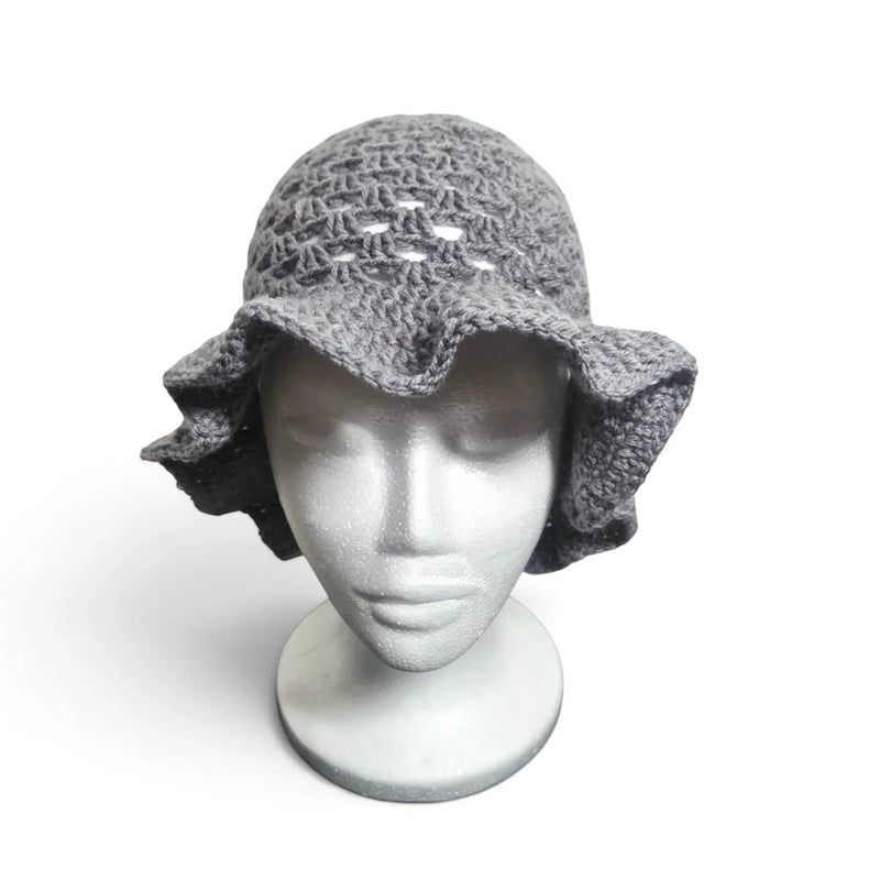 Handmade by Erika Liesel grey crochet bucket hat with a wide, wavy brim on a white mannequin head.