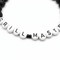 Handmade by Erika Liesel Grill Master bracelet with matte black lava stone beads and white letter beads on elastic