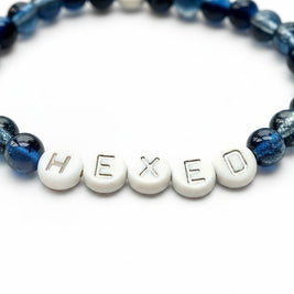 Handmade by Erika Liesel Hexed bracelet with midnight blue glass beads and white letter beads on elastic cord.