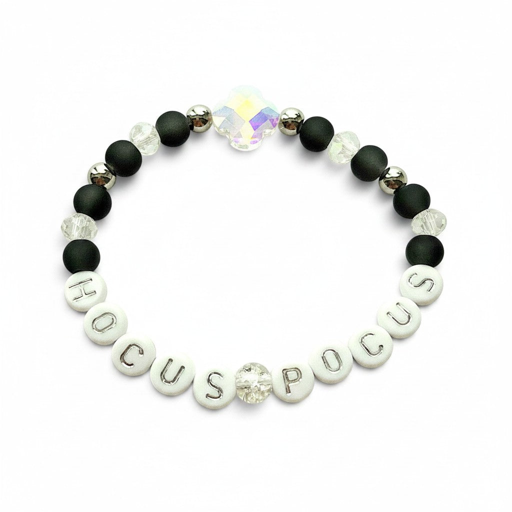 Handmade by Erika Liesel Hocus Pocus stretch bracelet with matte black beads, silver lettering, and crystal accents.