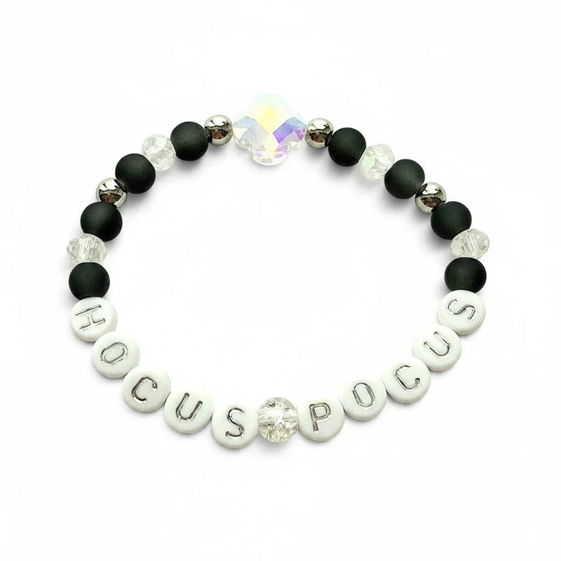 Handmade by Erika Liesel Hocus Pocus stretch bracelet with matte black beads, silver lettering, and crystal accents.