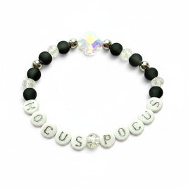 Handmade by Erika Liesel Hocus Pocus stretch bracelet with matte black beads, silver lettering, and crystal accents.