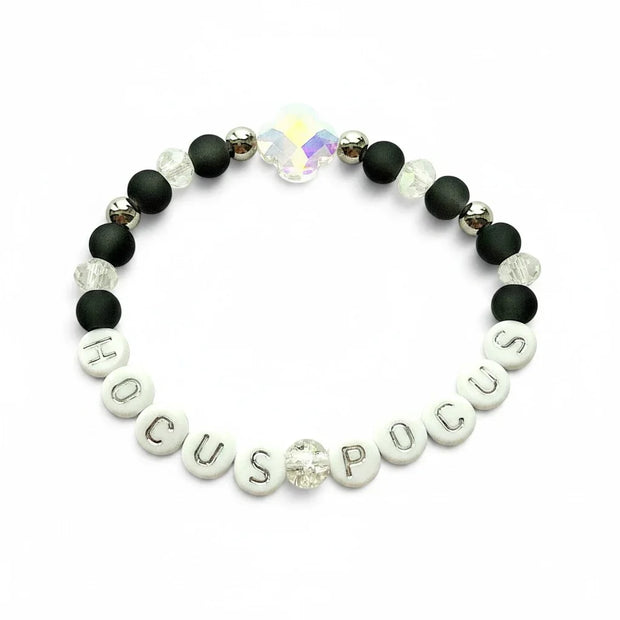 Handmade by Erika Liesel Hocus Pocus stretch bracelet with matte black beads, silver lettering, and crystal accents.