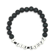 Handmade by Erika Liesel men's 8-inch stretch bracelet featuring matte black lava stone beads and I FIX STUFF letters.