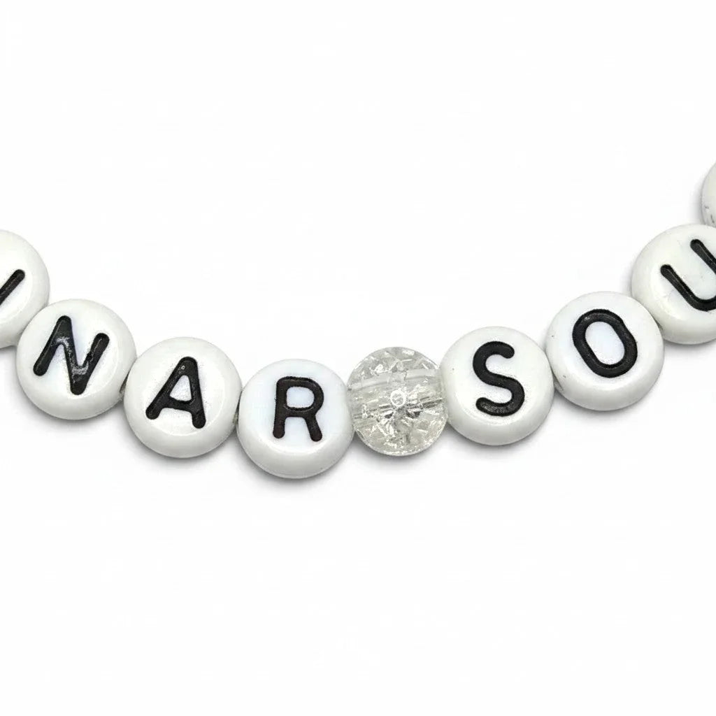Handmade by Erika Liesel Lunar Soul stretch bracelet featuring white letter beads and a clear marbled glass bead.