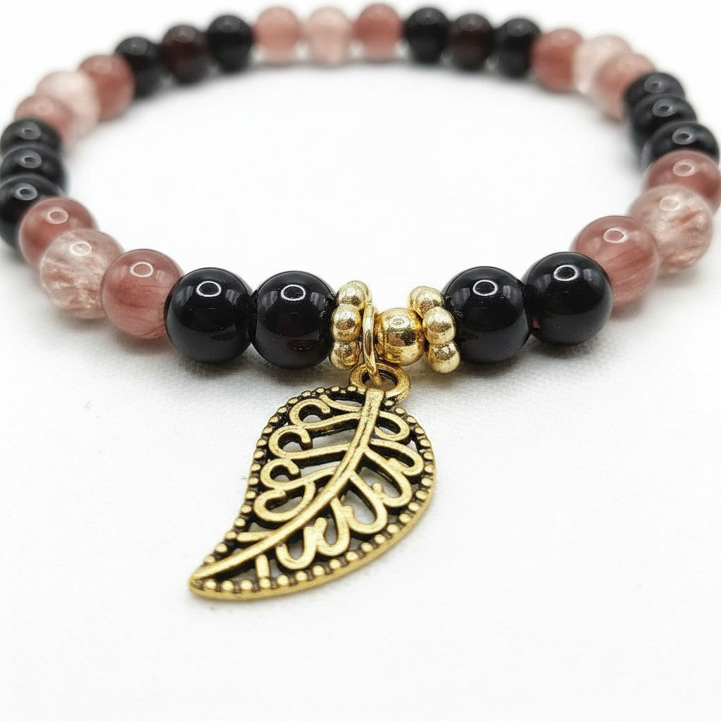 Handmade by Erika Liesel stretch bracelet with black, mulberry, and crackle glass beads and a gold-tone leaf charm.