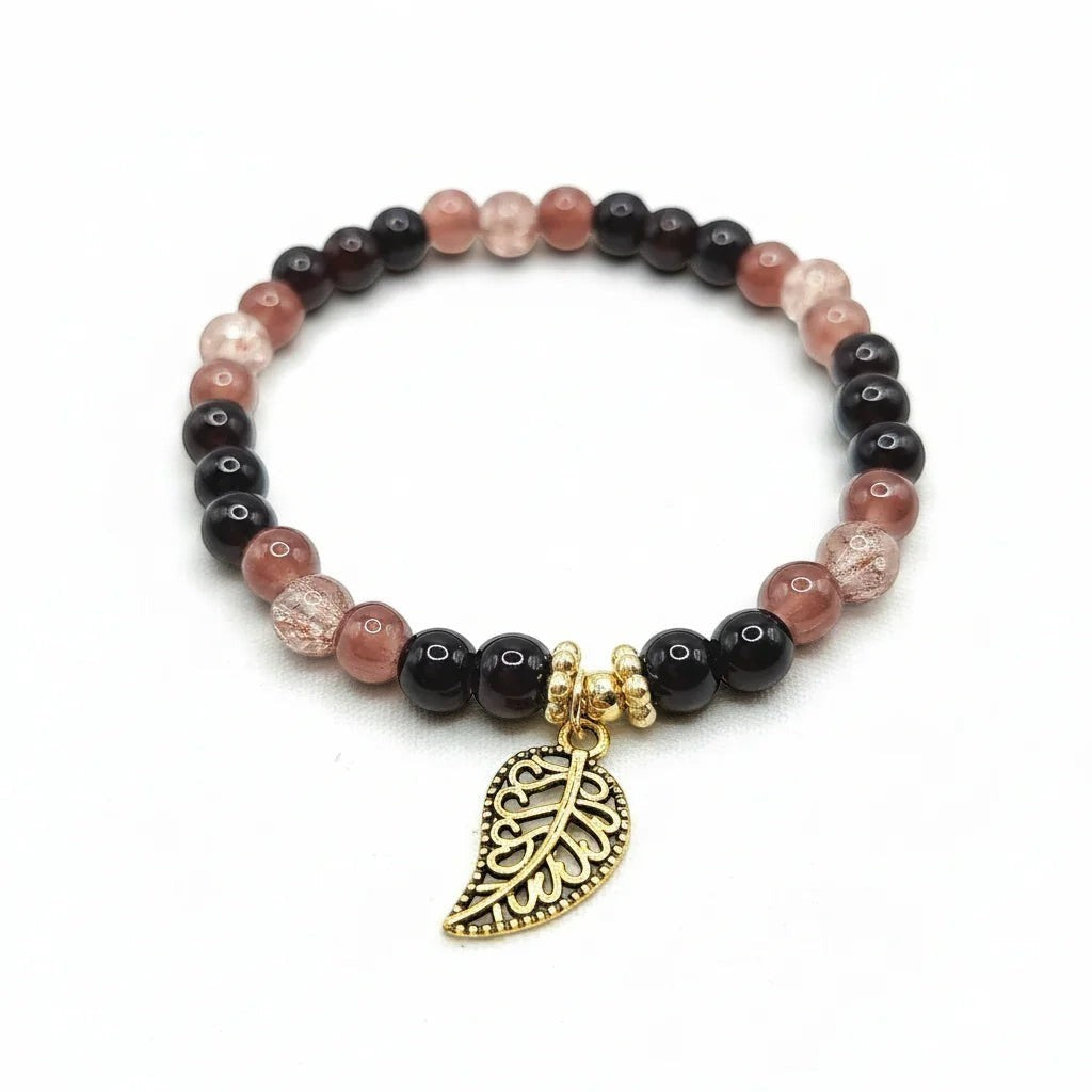 Handmade by Erika Liesel stretch bracelet with black, mulberry, and crackle glass beads and a gold-tone leaf charm.