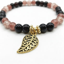 Handmade by Erika Liesel stretch bracelet with black, mulberry, and crackle glass beads and a gold-tone leaf charm.