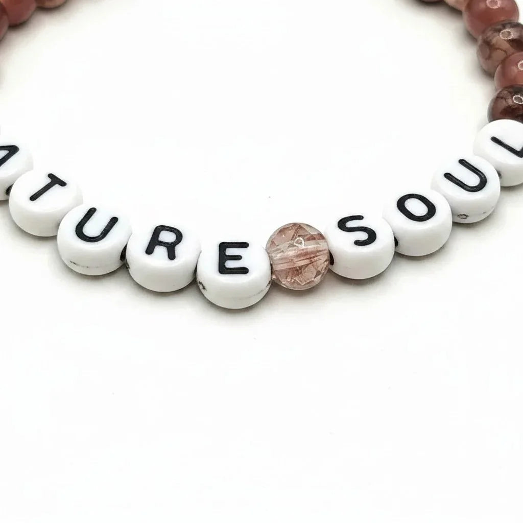 Handmade by Erika Liesel Nature Soul stretch bracelet with mauve and brown marbled glass beads and white letter beads.