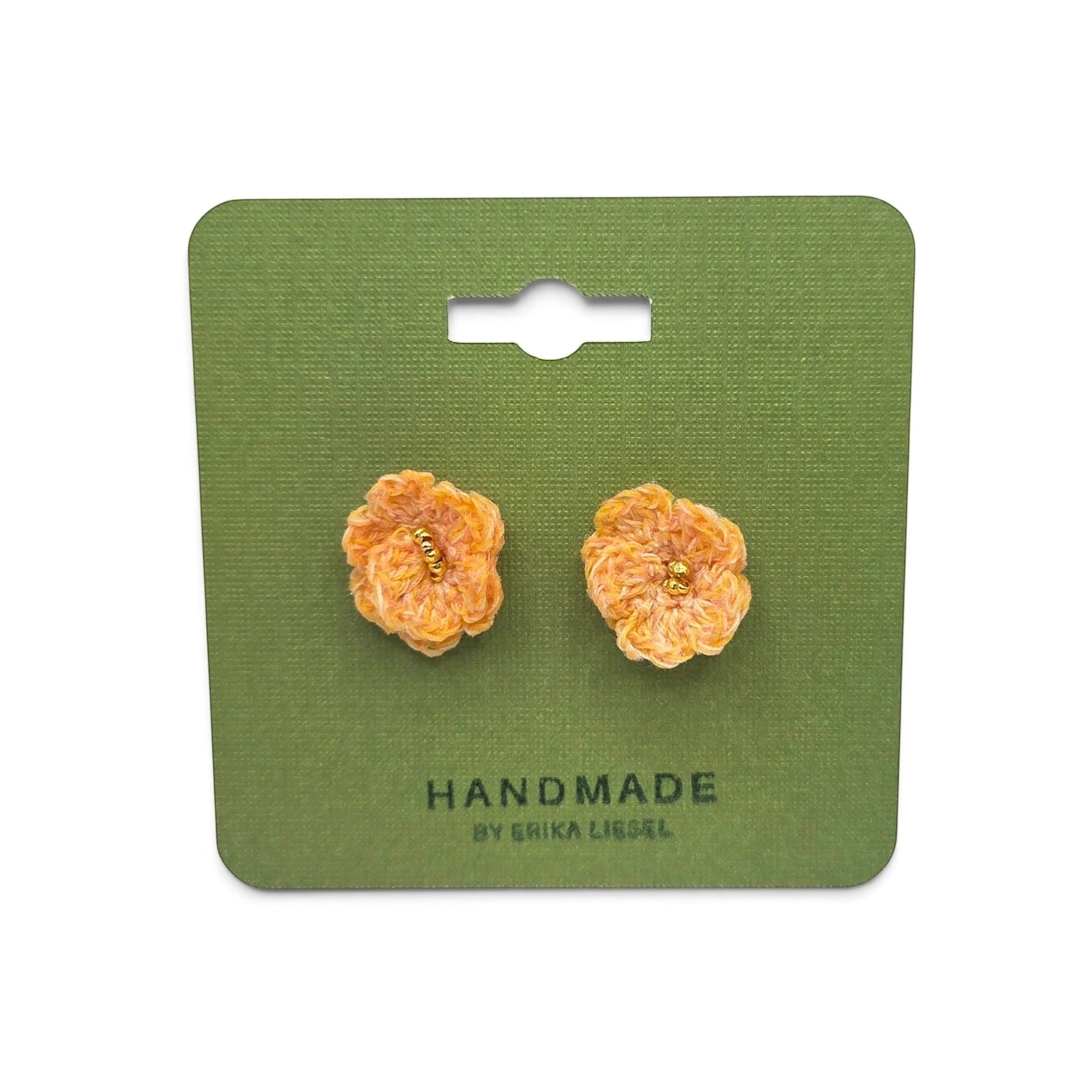 Handmade by Erika Liesel Bloom crochet flower earrings in peach with gold bead centers on a green display card.