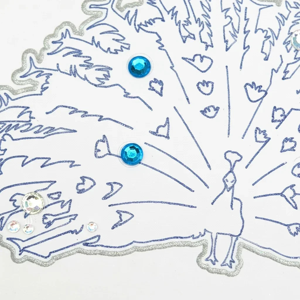 Handmade by Erika Liesel peacock greeting card with blue ink illustration, silver glitter accents, and gem details.