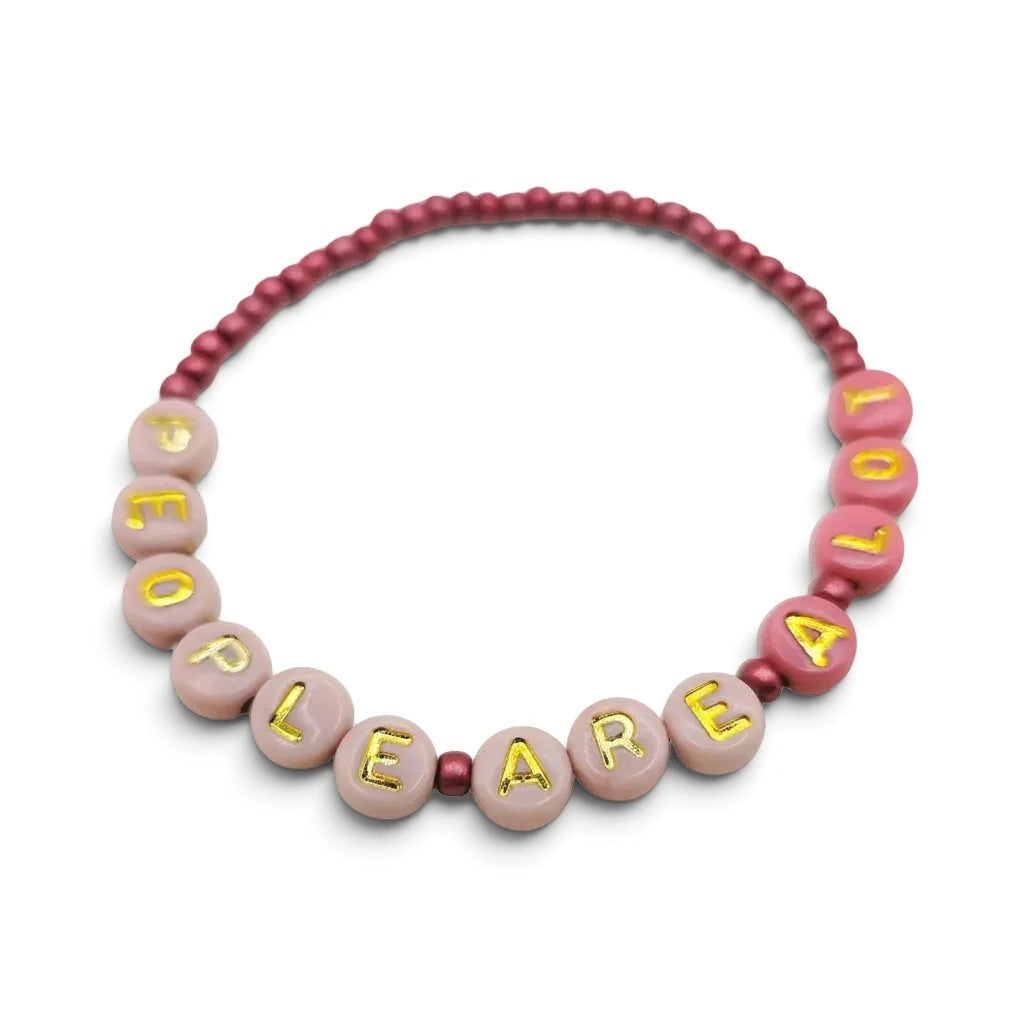 Handmade by Erika Liesel People Are A Lot bracelet with pink glass beads and gold letter beads on a stretch cord.