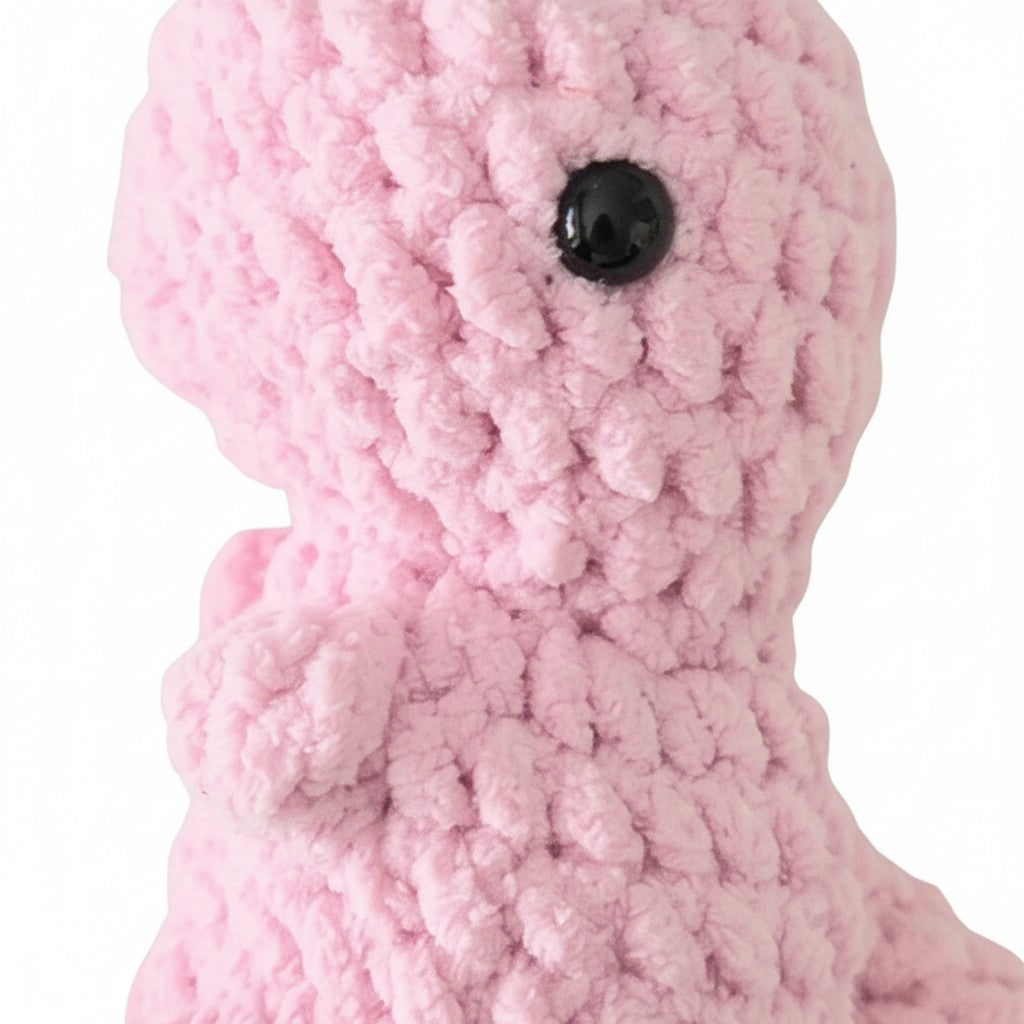 Handmade by Erika Liesel pink crochet dinosaur plushie made from soft chenille yarn with a black safety eye.