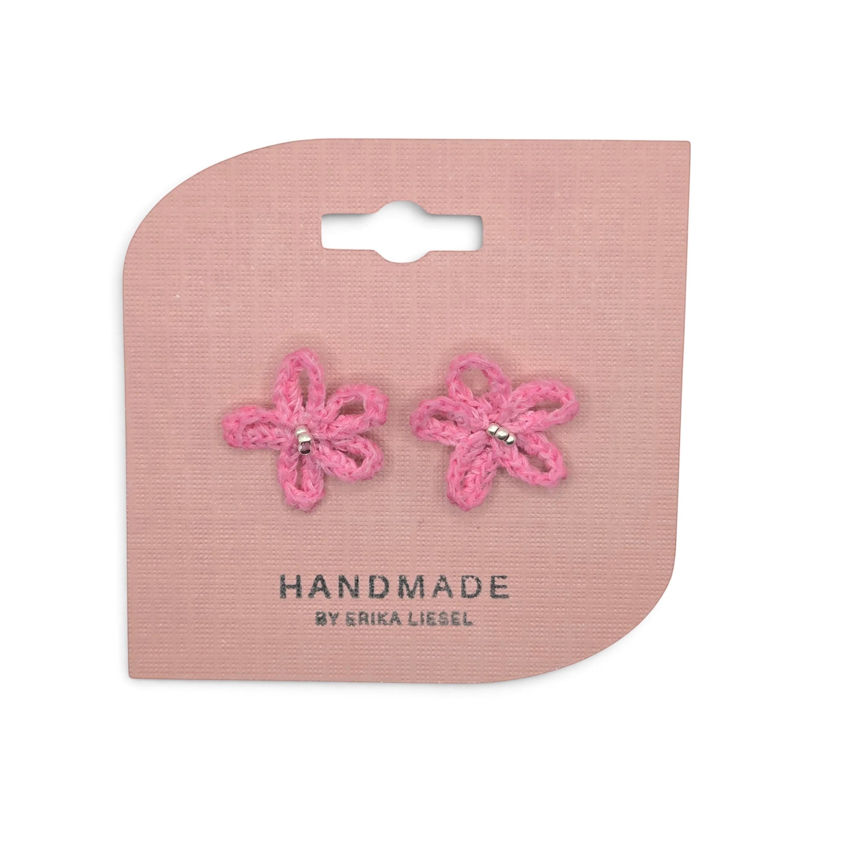 Handmade by Erika Liesel pink daisy bud crochet stud earrings with glass bead centers on a pink display card.