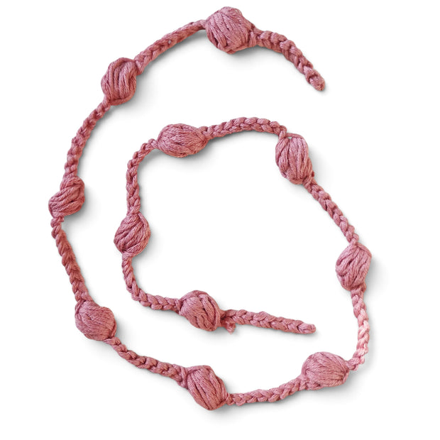 Handmade by Erika Liesel dusty pink crochet garland with textured yarn knots for cozy home decor and shelf styling.