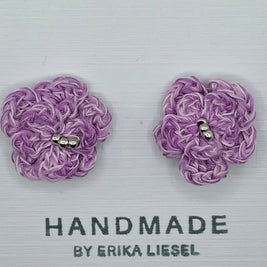 Handmade by Erika Liesel purple crochet flower stud earrings with glass bead centers on a white display card.