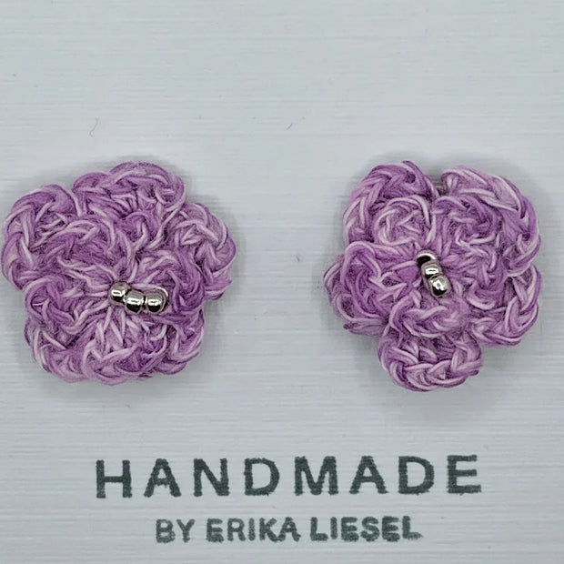 Handmade by Erika Liesel purple crochet flower stud earrings with glass bead centers on a white display card.