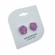 Handmade by Erika Liesel purple crochet flower stud earrings with delicate glass bead centers on a display card.