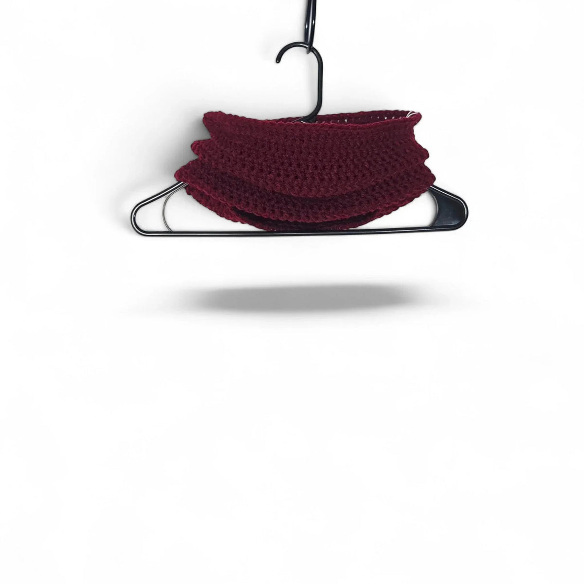 Handmade by Erika Liesel deep red crochet neck warmer hanging on a black hanger against a white background.