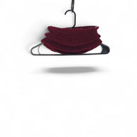 Handmade by Erika Liesel deep red crochet neck warmer hanging on a black hanger against a white background.
