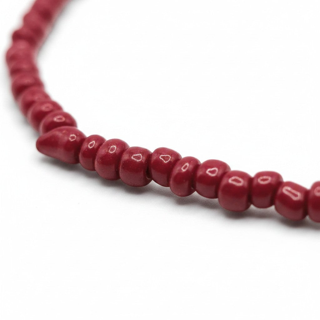 Handmade by Erika Liesel red glass bead stretch bracelet with a polished finish on a white background.