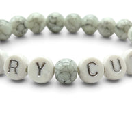 Handmade by Erika Liesel Scary Cute bracelet with gray marbled glass beads and white letter beads on elastic cord