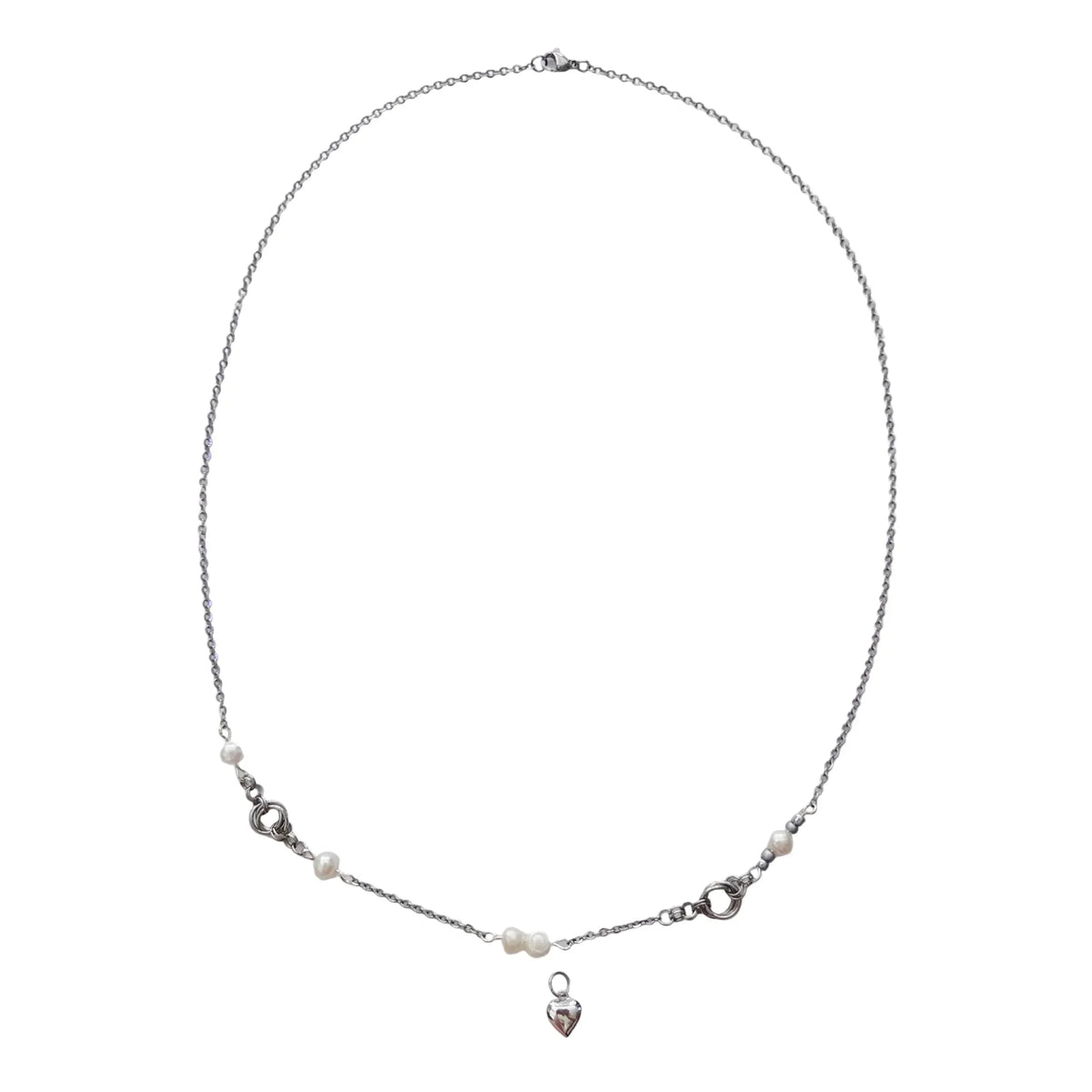 A delicate silver chain necklace with small white pearl-like beads and a small silver heart charm, displayed on a white card.