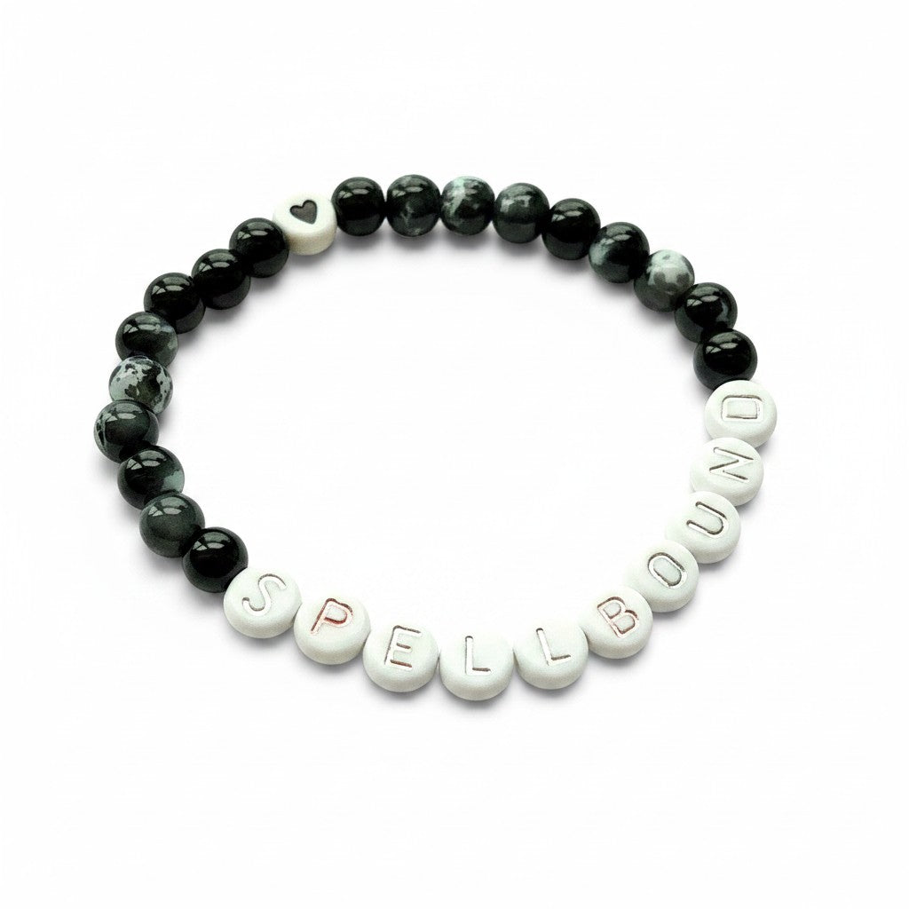 Handmade by Erika Liesel Spellbound stretch bracelet with black glass beads, silver letter beads, and a heart charm.