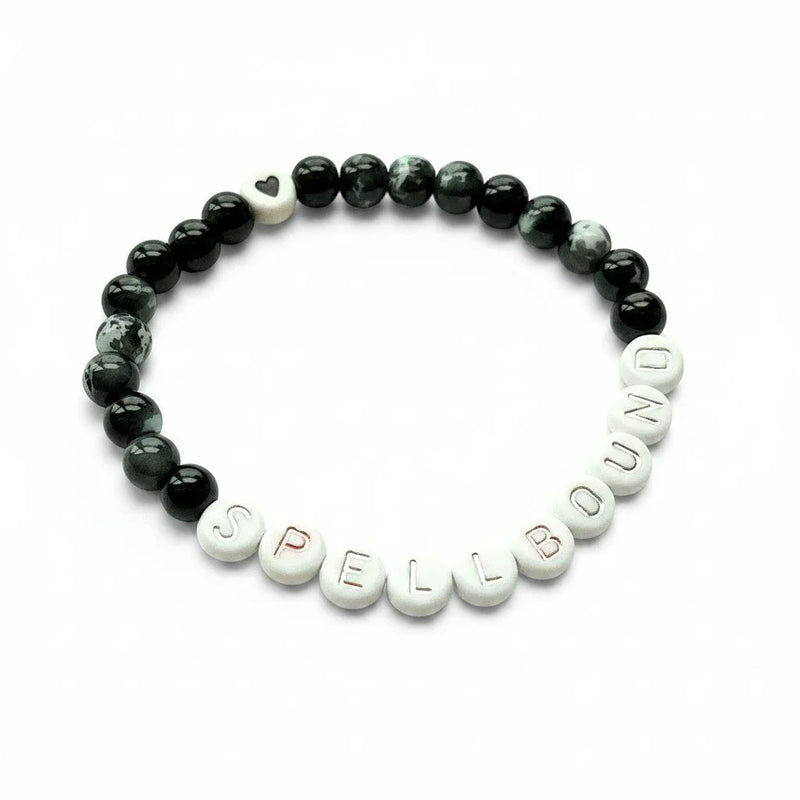 Handmade by Erika Liesel Spellbound stretch bracelet with black glass beads, silver letter beads, and a heart charm.