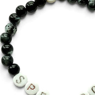 Handmade by Erika Liesel Spellbound stretch bracelet with glossy black glass beads and silver lettered beads