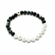 Handmade by Erika Liesel Spellbound stretch bracelet with black glass beads, silver letter beads, and a heart charm.