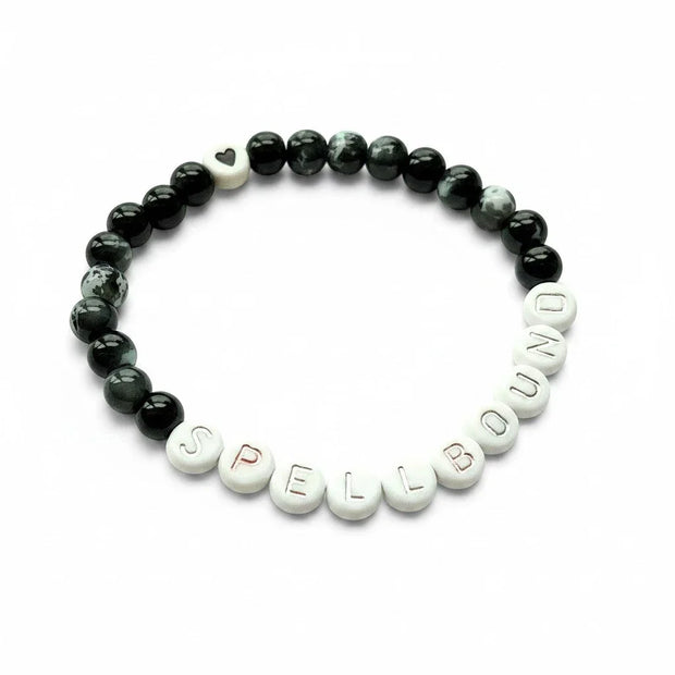 Handmade by Erika Liesel Spellbound stretch bracelet with black glass beads, silver letter beads, and a heart charm.