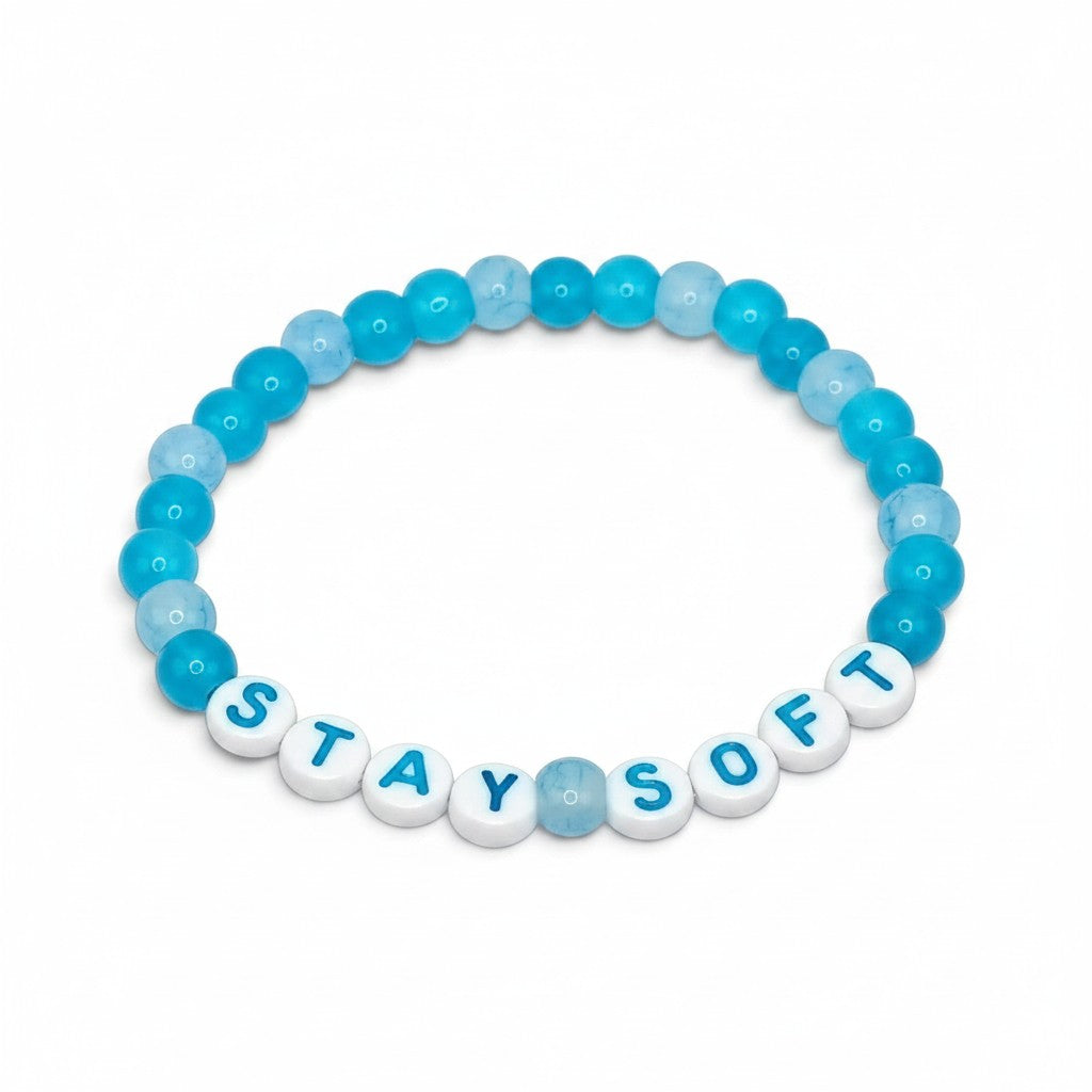 Handmade by Erika Liesel Stay Soft stretch bracelet with bright and pale blue glass beads and white letter beads.