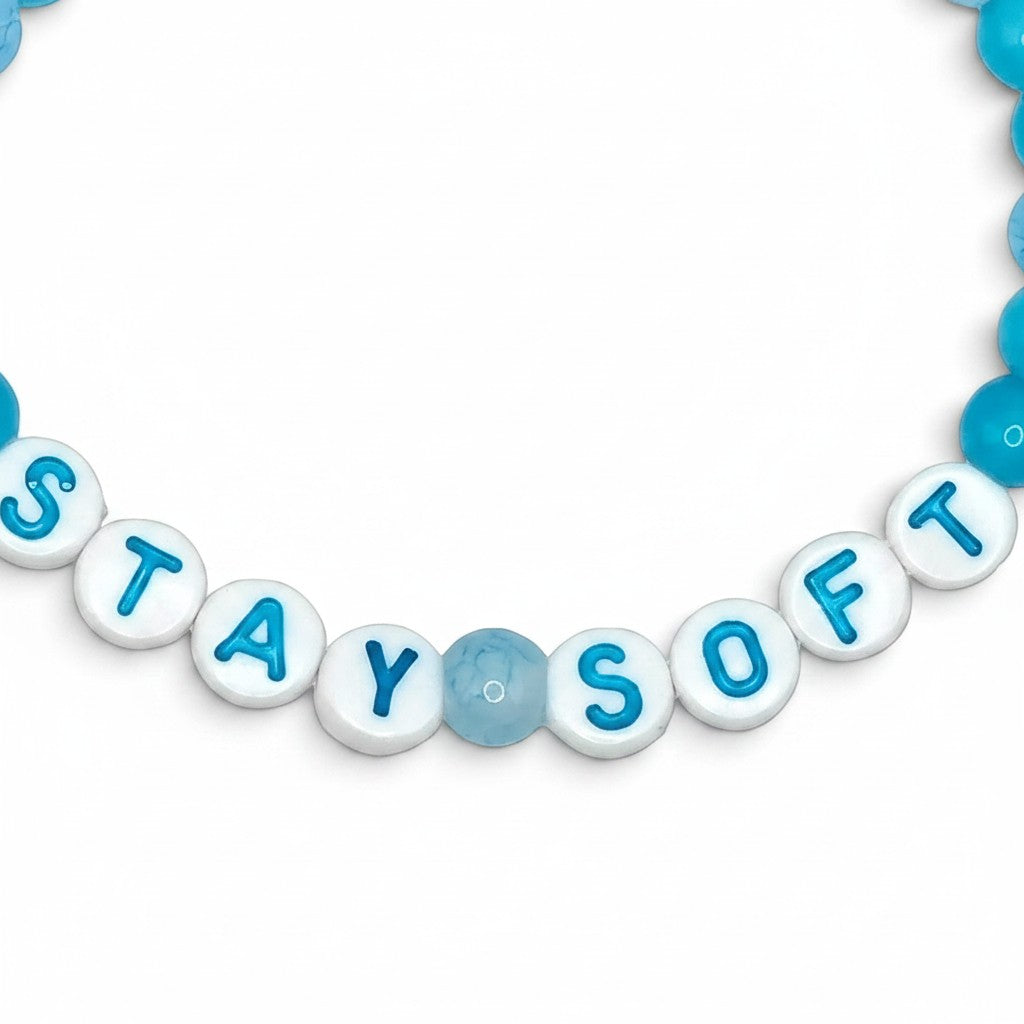 Handmade by Erika Liesel Stay Soft stretch bracelet with bright and pale blue glass beads and white letter beads.