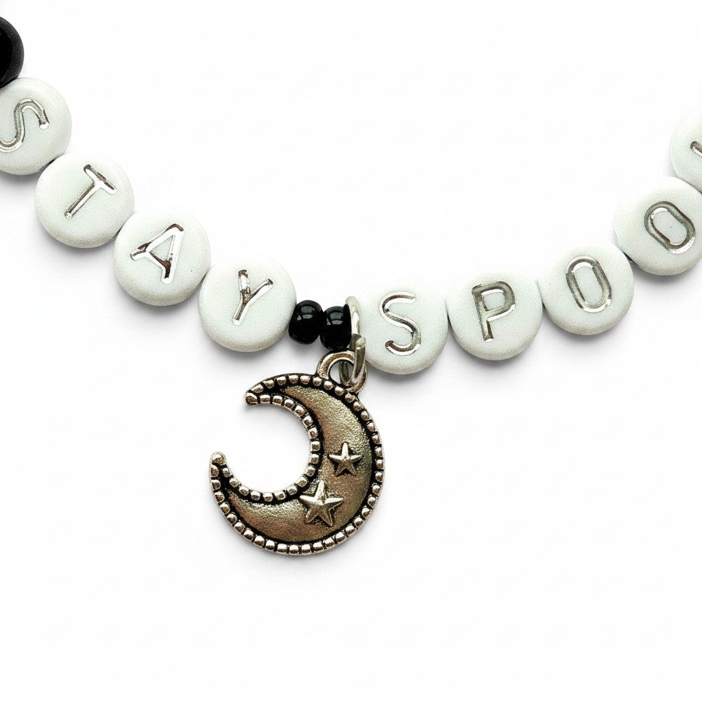 Handmade by Erika Liesel Stay Spooky bracelet with white letter beads, black glass beads, and a silver moon charm.