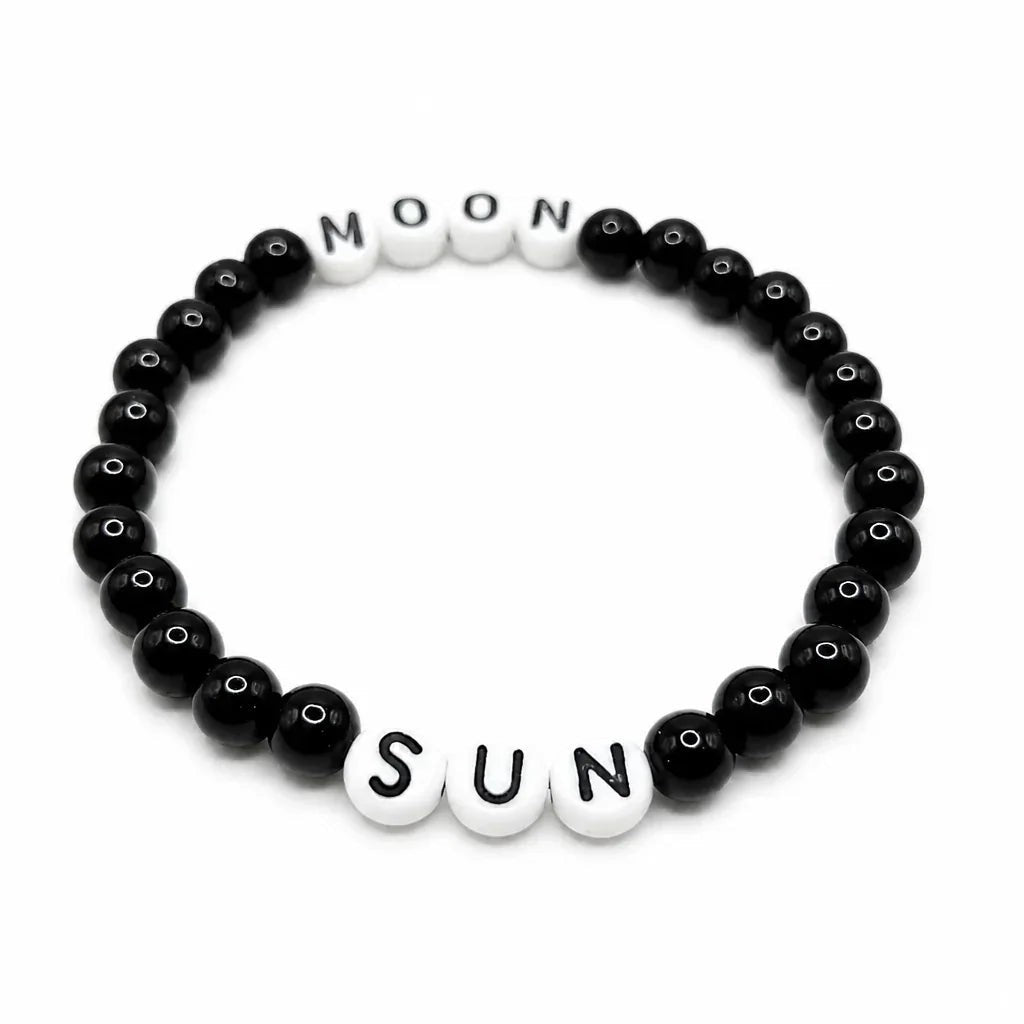 Handmade by Erika Liesel Sun & Moon stretch bracelet with black glass beads and white letter beads on elastic cord.