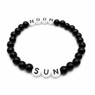 Handmade by Erika Liesel Sun & Moon stretch bracelet with black glass beads and white letter beads on elastic cord.