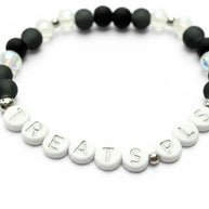 Handmade by Erika Liesel Treats Pls stretch bracelet with matte black glass beads and silver-lettered white beads.