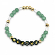 Handmade by Erika Liesel Worthy stretch bracelet with green crystal beads, gold accents, and black letter beads.