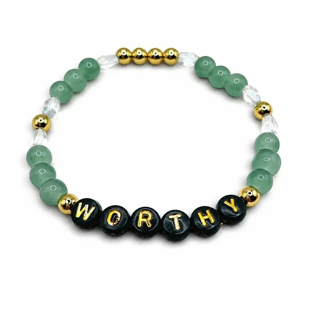 Handmade by Erika Liesel Worthy stretch bracelet featuring green crystal beads, 18K gold accents, and black letter beads.