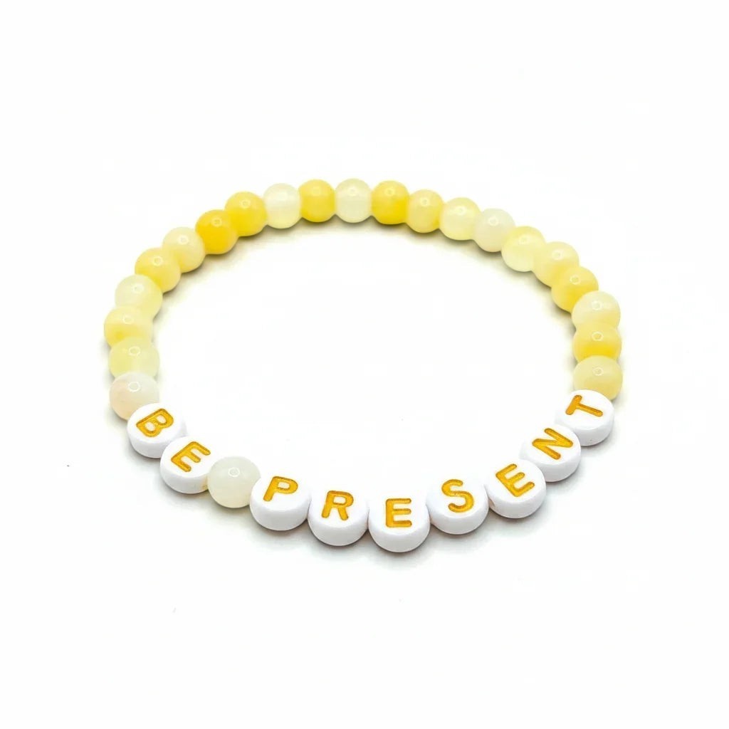 Handmade by Erika Liesel Be Present bracelet with soft yellow glass beads and white letter beads on elastic cord.