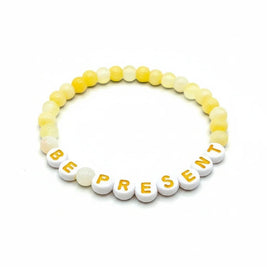 Handmade by Erika Liesel Be Present bracelet with soft yellow glass beads and white letter beads on elastic cord.
