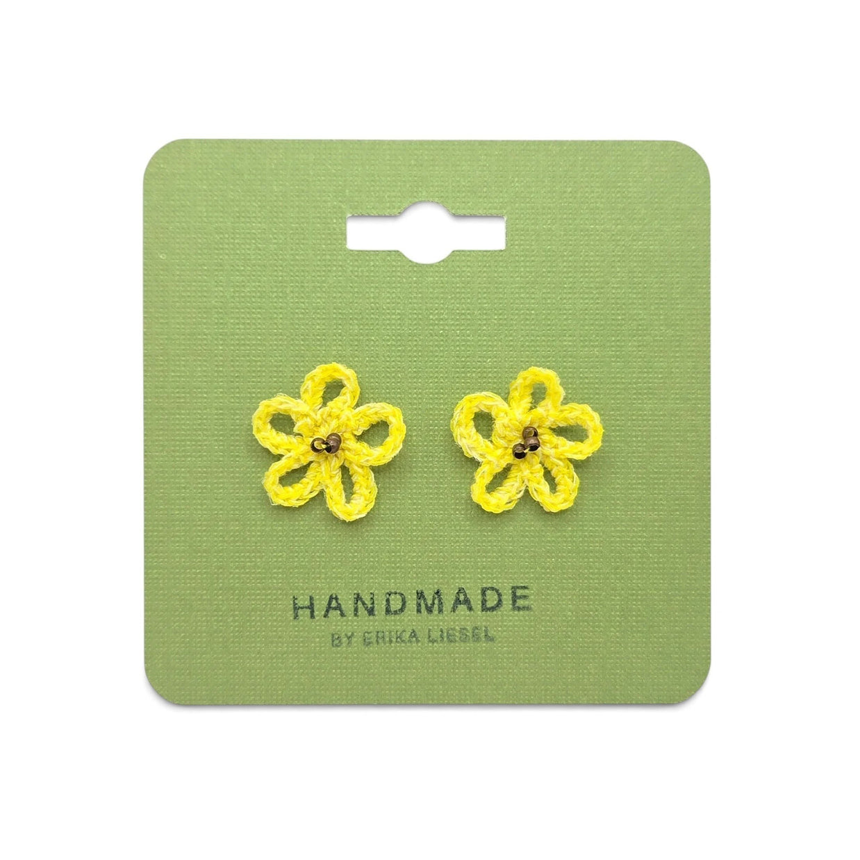 Handmade by Erika Liesel yellow daisy crochet stud earrings with glass bead centers on a green display card.