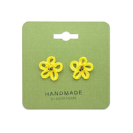 Handmade by Erika Liesel yellow daisy crochet stud earrings with glass bead centers on a green display card.