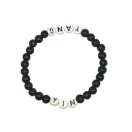 Handmade by Erika Liesel stretch bracelet with black glass beads and white letter beads spelling Yin and Yang